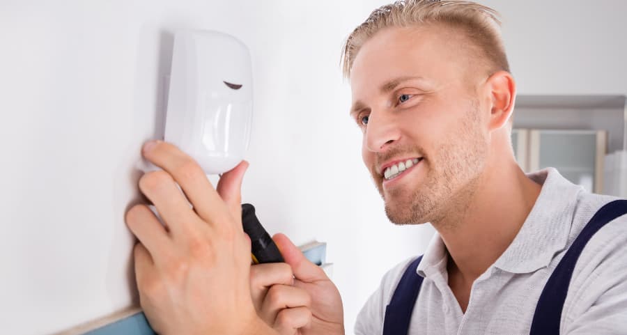 Man placing a motion detector inside a home